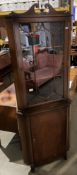 A mahogany reproduction freestanding corner cupboard with upper glazed doors over single door base,