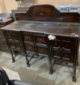 An early 20th century oak sideboard with short raised back over two centre drawers flanked by