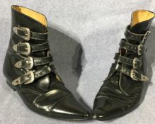 Pair of black leather winklepicker ankle boots each with four silver-coloured buckles and belt ends,