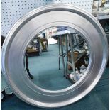 A large circular mirror, with silver coloured frame.