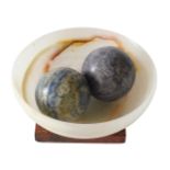 A turned agate bowl, 11cm diameter, two purple stone balls, and a simulated marble stand, 8cm