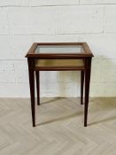 A mahogany bijouterie table with four glass panels and a rising glazed top