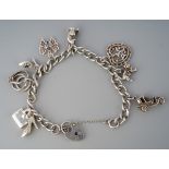 A charm bracelet. The curb link chain with padlock clasp and charms, padlock hallmarked silver,