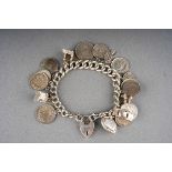 Silver charm bracelet with heart shaped locket, approx. 18 charms including coins. Gross total