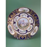 An 18th century Sevres plate centrally painted with a child, food bowl in hand seated amongst