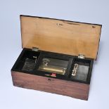 Wooden music box made of dark wood with a black lacquered interior. A brass cylinder mechanism under