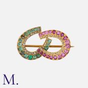 An Antique Ruby, Emerald and Diamond Brooch in yellow gold. Designed as two horse shoes, one set