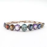 An Edwardian Gem-stone Bracelet, claw-set gems of different cuts including blue zircon, sapphire,