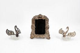 An art nouveau decorated silver mirror, together with two glass and silver swan shaped figures