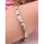 A 9ct two tone gold diamond tennis bracelet designed as alternating yellow and white gold links