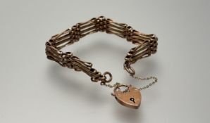 An Edwardian 9ct rose gold gate link engraved bracelet with 9ct gold heart shaoed padlock and safety