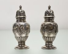 A pair of Victorian London silver baluster pepperettes with chased bows and ribbons on stepped
