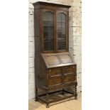 An early 20th century bureau bookcase, twin-glazed panel doors enclosing shelves to interior, on a