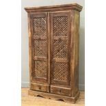 An Indian-style hardwood and brass-mounted armoire, twin lattice panel doors enclosing two shelves
