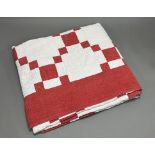 A red and light pink Durham quilt in a checkerboard design with hand-stitched flowers in white