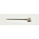 A diamond and seed pearl stick pin, c. 1900, the central round brilliant-cut stone within a band