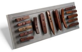 ASSORTMENT OF FIFTEEN MAHOGANY SHIP'S CLEATS, mounted on a painted board, 28 x 83cms Provenance:
