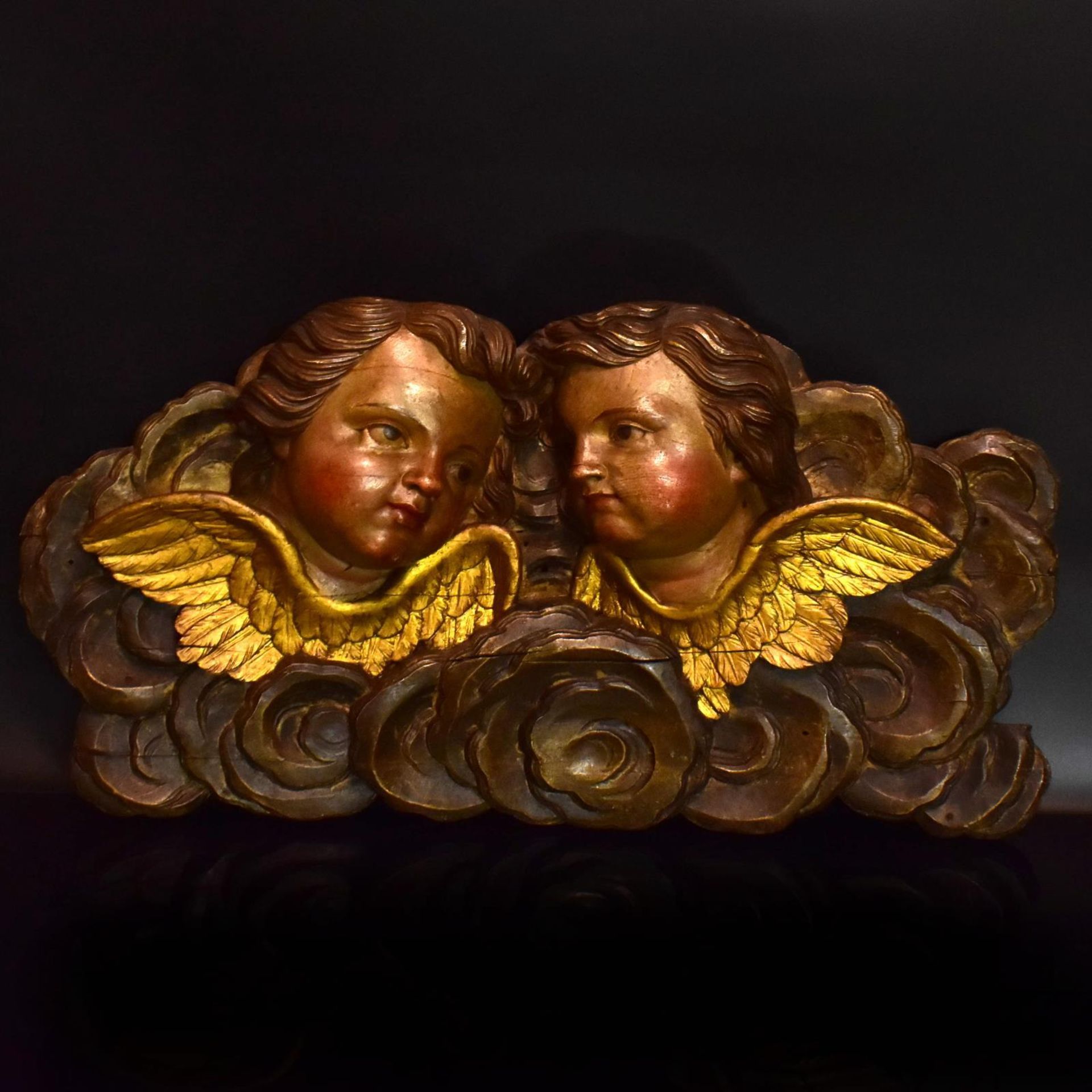 Zwei Puttenköpfe in Wolkenbank. 19./20. Jh. | Holz, geschnitzt, Farb- und Goldfassung.