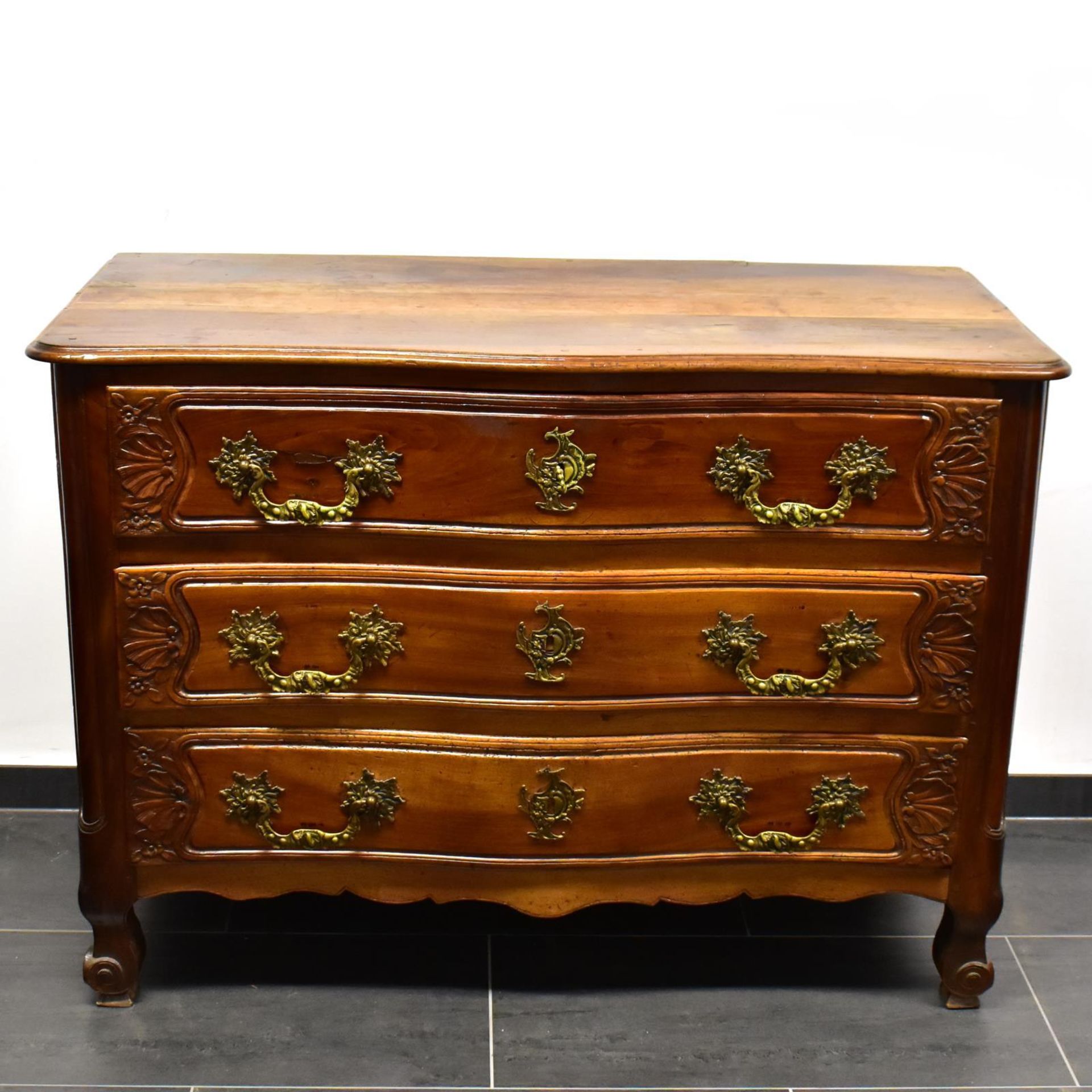 Kommode. Um 1900, Barockstil | Nussbaum und andere Hölzer. Stoff. Messing.