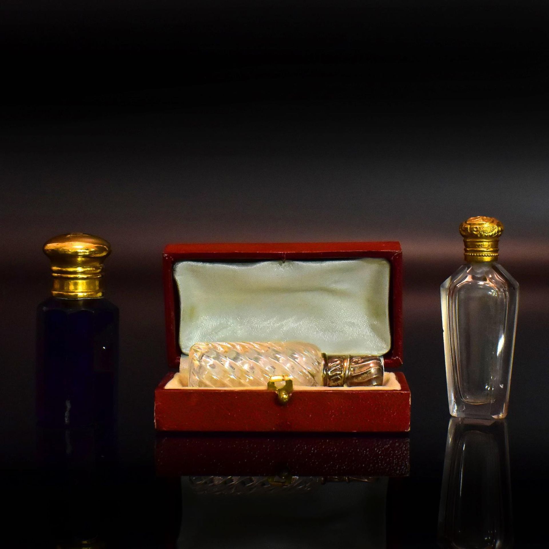 Drei Flakons. 19./20. Jh. | Farbloses bzw. blaues Glas, Silber- bzw. Metallmontierungen.