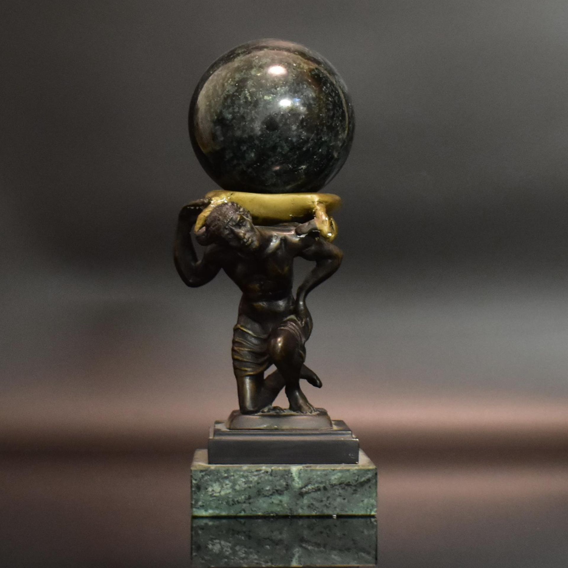 Kniender Atlas. 19./20. Jh. | Bronze, patiniert. Grüne Marmorkugel und -plinthe.