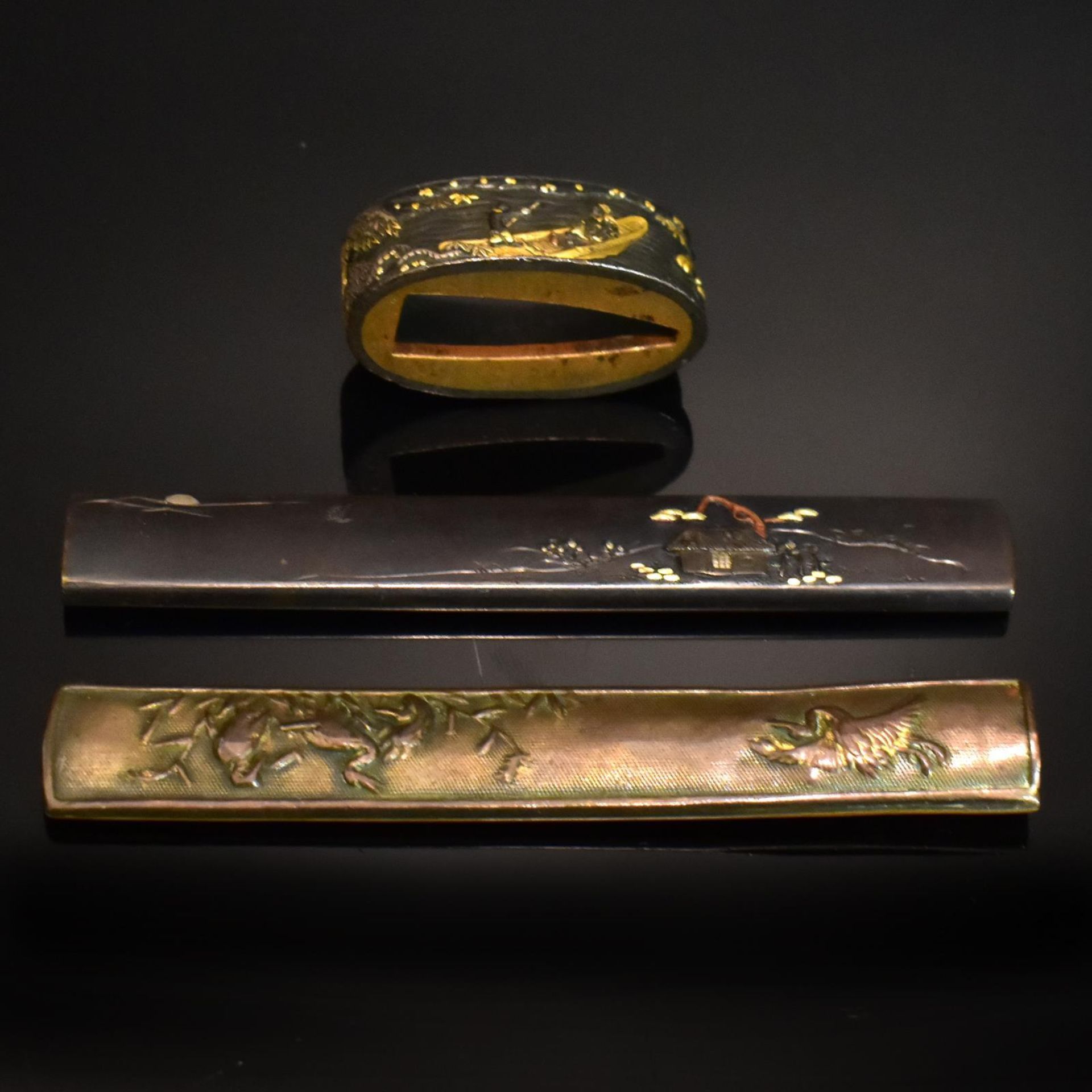 Fuchi und zwei Kozuka. Japan, späte Edo / Meiji | Bronze, Gold, Silber, Shakudo (wohl).
