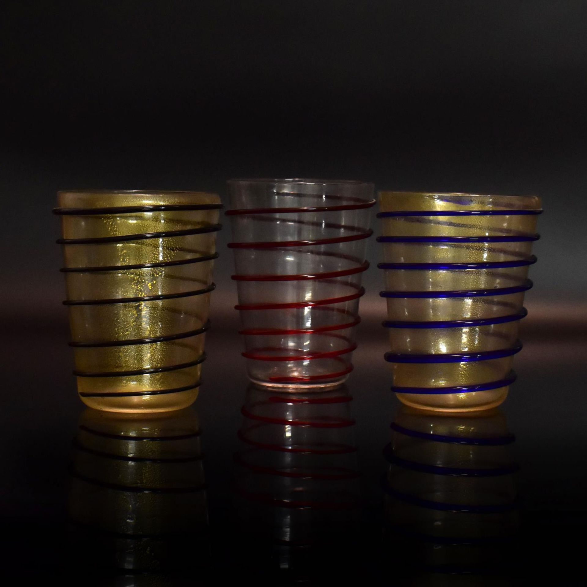 Zwölf Bechergläser. 20. Jh. | Verschiedenfarbiges Glas, teils mit Goldflittereinschmelzungen.