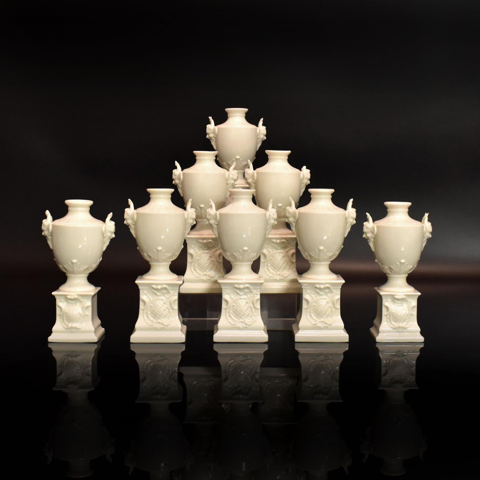 Acht Ziervasen auf Postamenten. Nymphenburg | Porzellan, weiß.