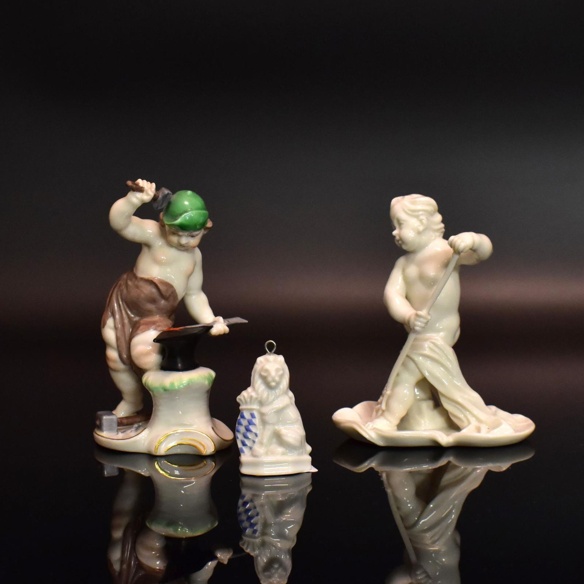 Zwei Putten und Anhänger. Nymphenburg | Porzellan, farbig staffiert bzw. weiß.