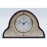 An Italian silver and veneer arched desk clock, having embossed floral and enamel decoration, with