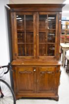 A modern hardwood bookcase in the period style, having double cupboard under, dimensions H190 W102