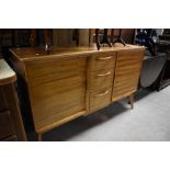 A vintage sapele sideboard of stylised design having central drawer section flanked by cupboards,