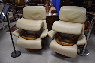 A pair of modern cream leather stressless easy chairs and matching footstools