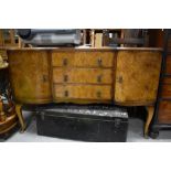 An early to mid 20th Century walnut sideboard having central drawers flanked by cupboards, on