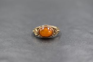 A 9ct gold amber set ring, the oval amber cabochon in a bezel setting, having decorative pierced
