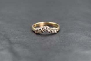 A 9ct gold cubic zirconia set wishbone ring, the seven round cut cubic zirconia in a wishbone
