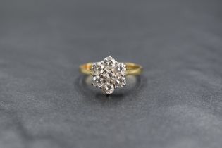 An 18ct gold daisy cluster ring having seven brilliant cut diamonds totalling approx 1ct in a claw