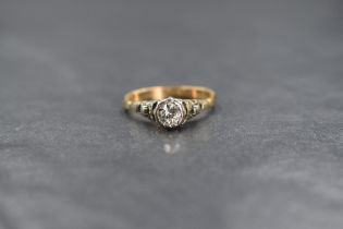 A yellow metal diamond solitaire ring having a 0.25ct stone in a collared mount to raised moulded