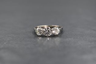An 18ct white gold and platinum three stone diamond set ring, the graduated round brilliant cut