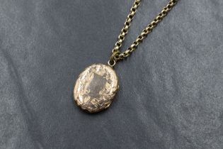 A rose gold coloured oval locket having engraved foliate decoration on a belcher link chain, no