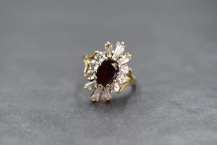 A 9ct gold paste set cluster ring, the central oval cut red paste in a twelve cubic zirconia