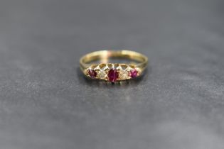 A yellow metal ruby & diamond ring having three small graduated rubies interspersed by two old cut