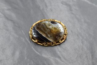 A large oval brown striped agate brooch in a decorative pinchbeck mount