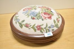 A contemporary mahogany and needlepoint footstool, having soft pink rose and foliage decoration,