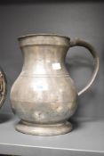 A large Victorian pewter quart pitcher, featuring a bulbous body and a large thumb-piece handle,