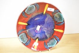 A 20th-century Poole Pottery 'volcano' charger, featuring hand painted vibrant reactive glazes of