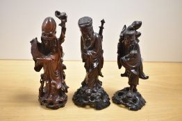 A group of three well carved Chinese hardwood immortals, each carved with flowing robes, two mounted