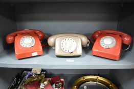 Three mid to late 20th-century rotary dial landline telephones, to include two red and one beige