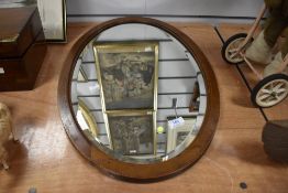 A large early 20th-century oval wooden mirror, with decorative inlay, beveled glass, and hanging