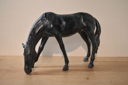 A large patinated metal stallion study, posed head down, measuring 24cm tall.